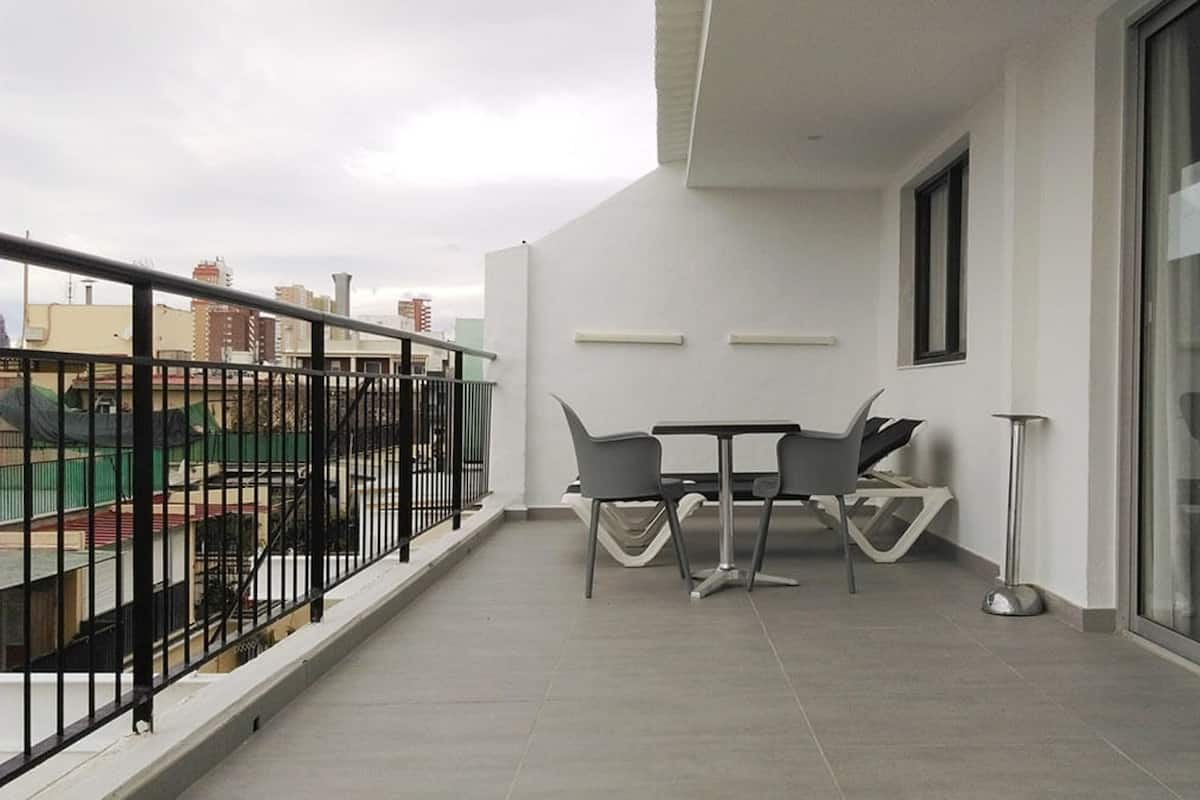 Un balcón con una mesa y sillas, una lámpara de pie y vistas de la ciudad.