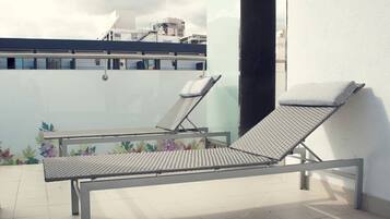 Terraza en la azotea con dos tumbonas y suelo de baldosas.