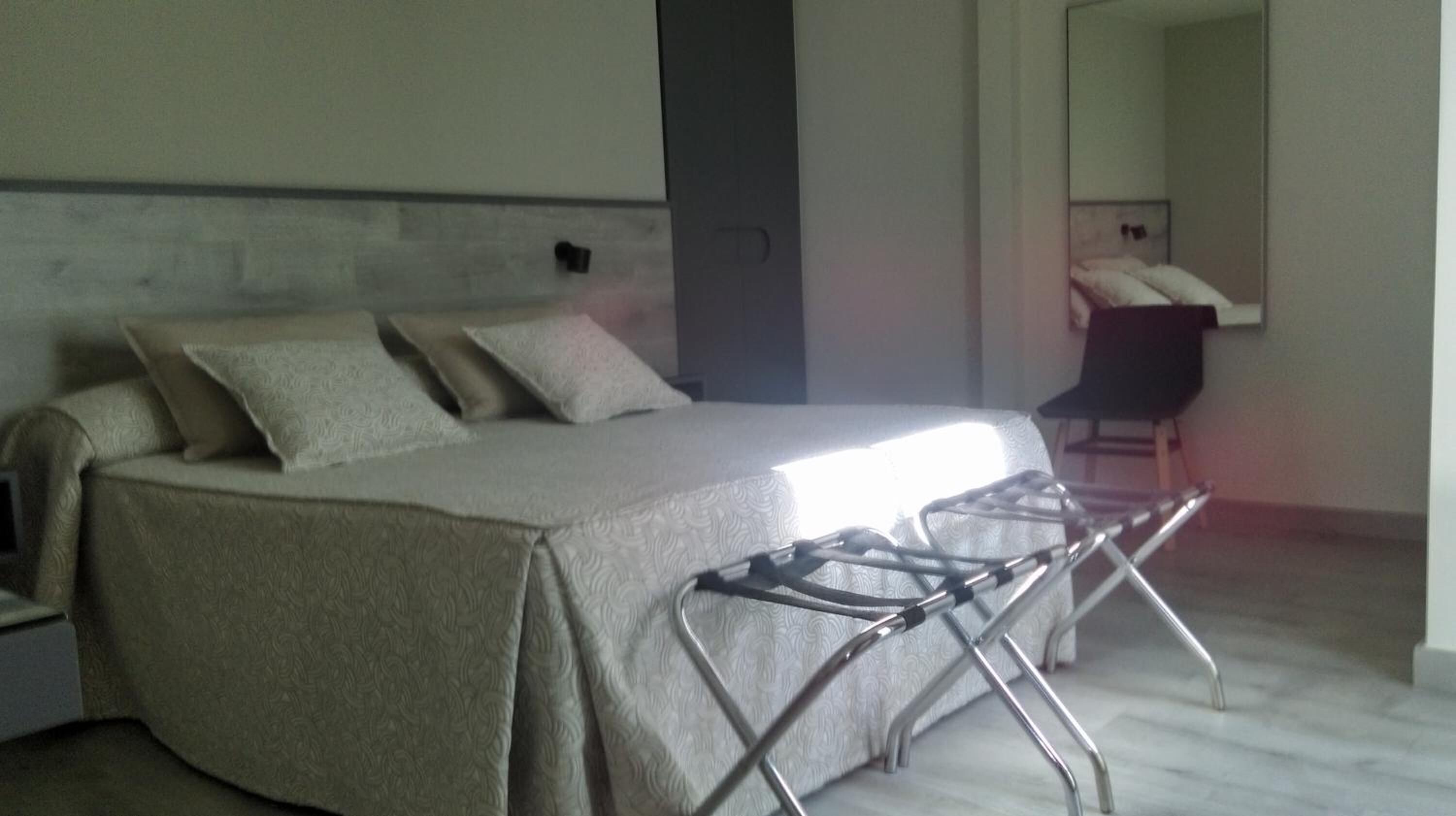 Un dormitorio moderno con cama, una silla y un espejo.