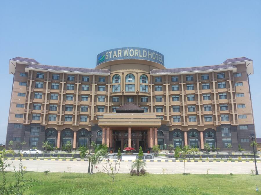 Un hotel grande con un letrero llamativo que dice “STAR WORLD HOTEL”. Cuenta con una fachada simétrica con múltiples ventanas y balcones.
