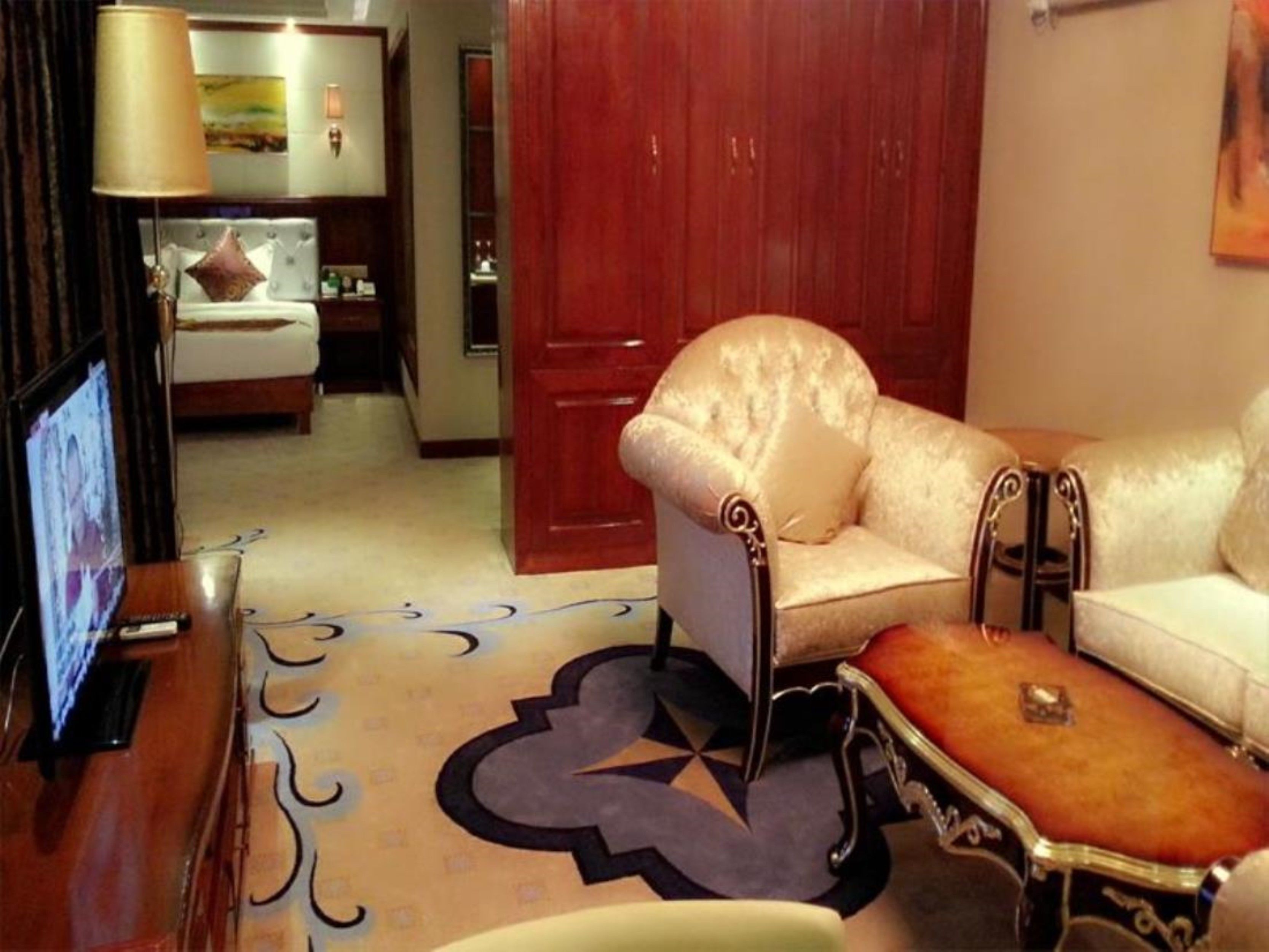 A hotel room with a sofa, a small table, a TV, and a bed.