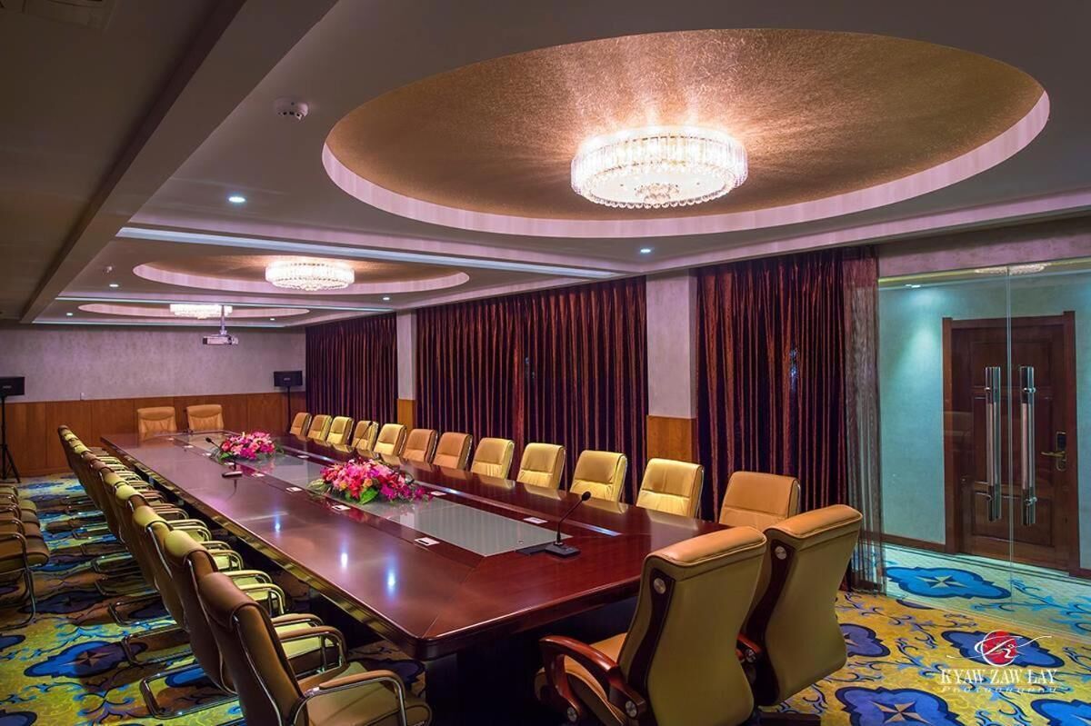 A conference room with a long table, multiple chairs, and a chandelier.