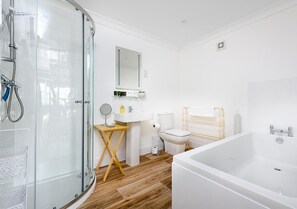 A modern bathroom with a glass shower enclosure, a white bathtub, a wooden vanity, and a toilet. - Sherbourne House (Attleborough)