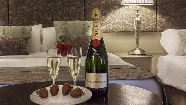 Una botella de Moët & Chandon Champagne sobre una mesa con dos copas y fresas bañadas en chocolate.