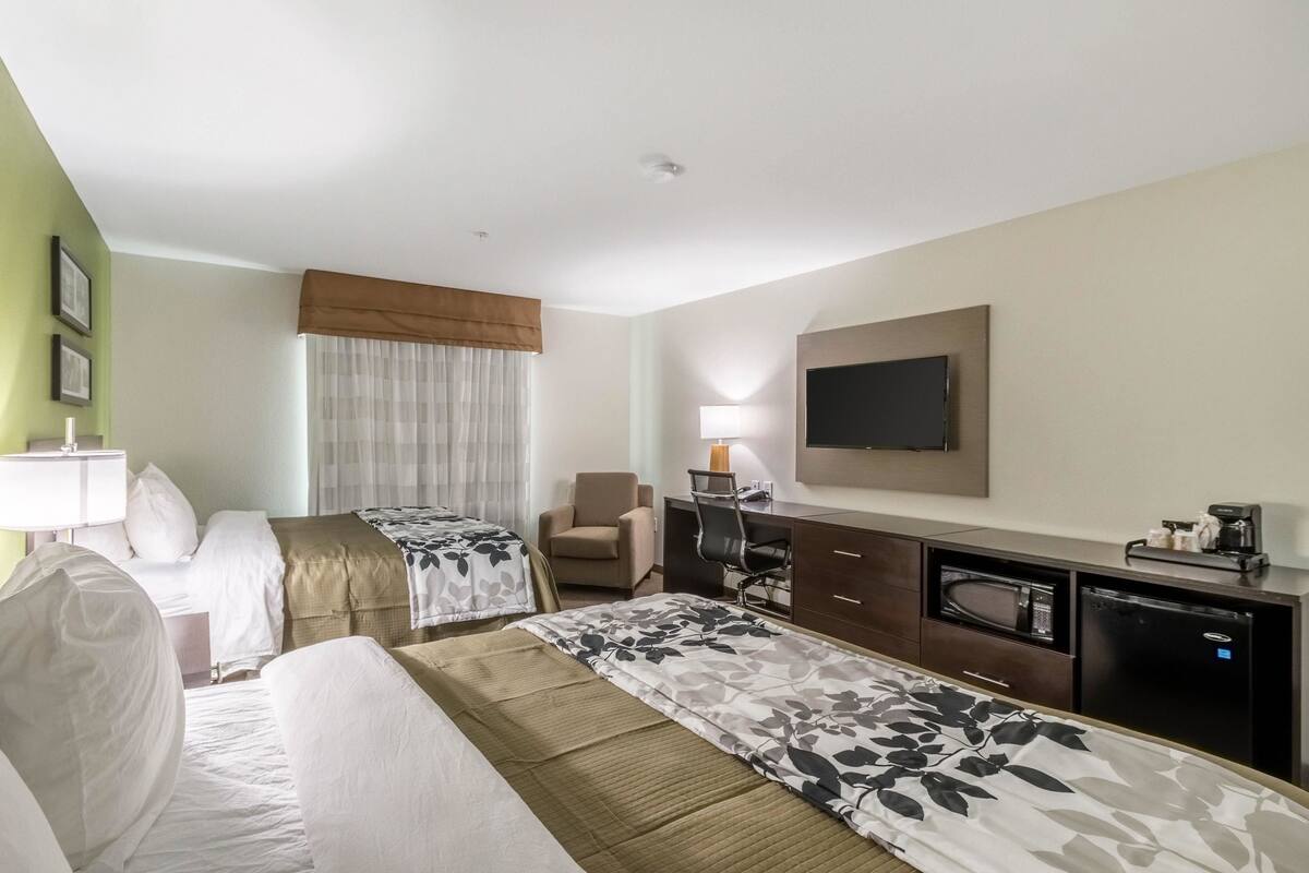 A hotel room with two beds, a desk with a computer, a TV, and a microwave.