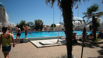Una piscina al aire libre de temporada, sombrillas