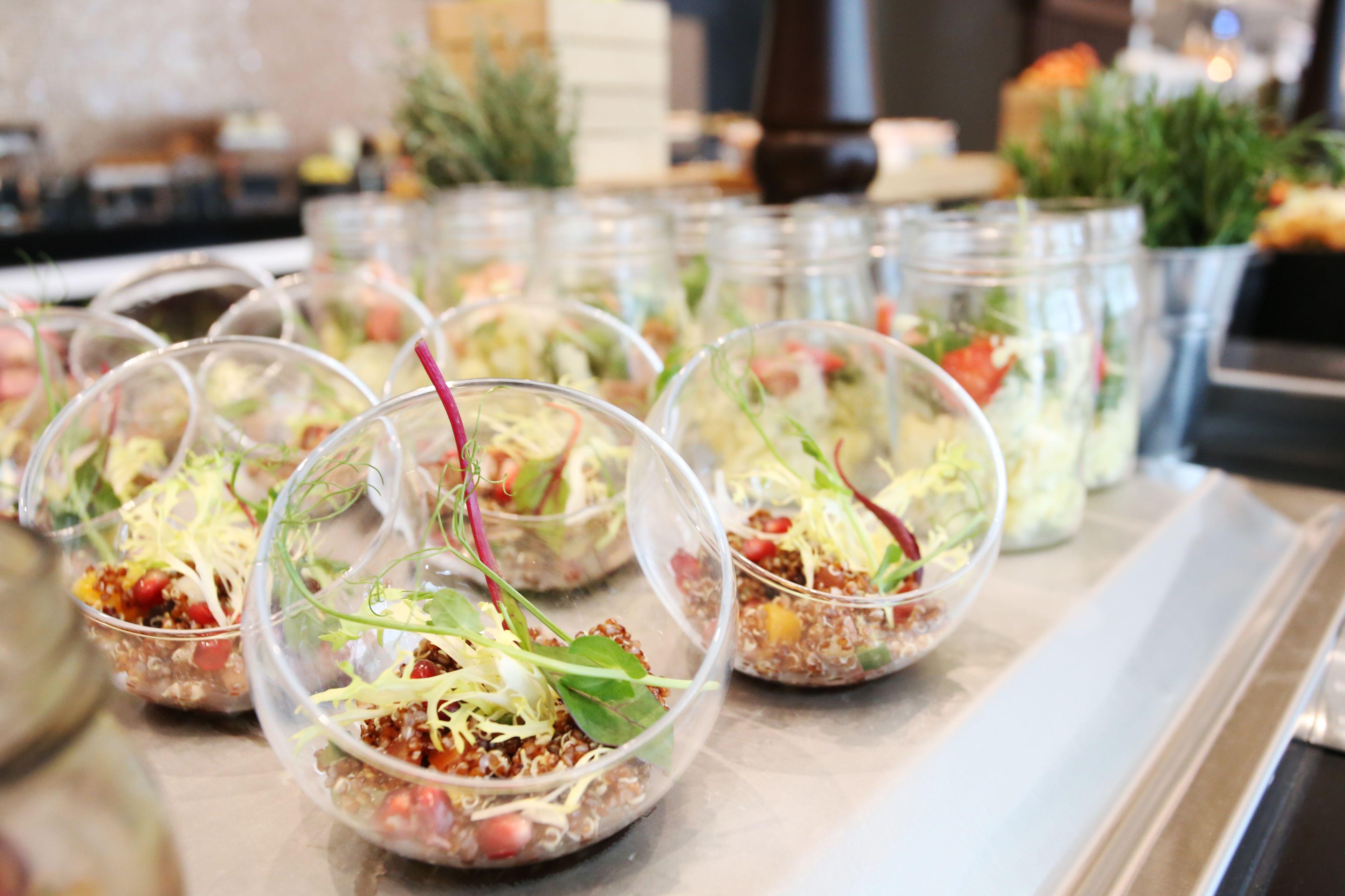 Una mesa de buffet con recipientes de vidrio que contienen diversos alimentos.