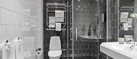 A modern bathroom with a glass-enclosed shower, a white toilet, and a large sink with a mirror.