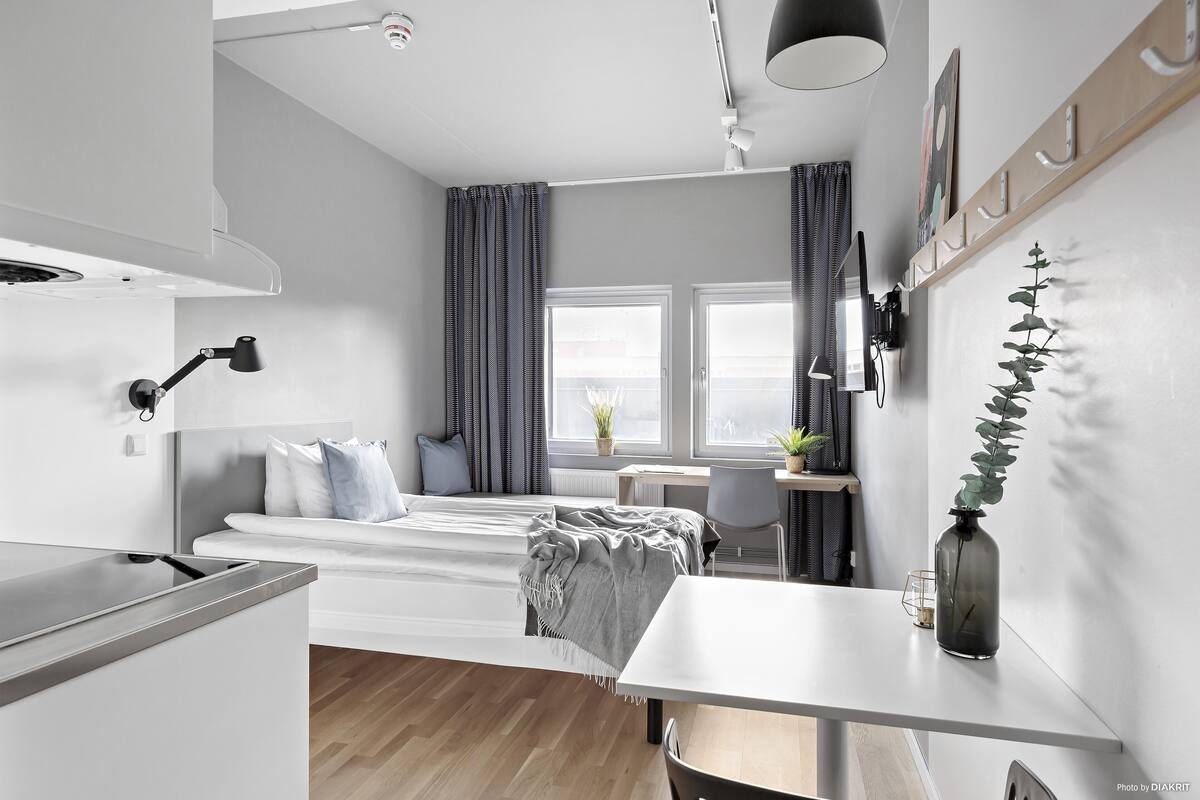 Un dormitorio moderno y funcional con cama, mesita de noche y escritorio con silla.