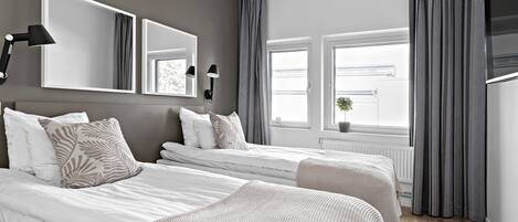 Un dormitorio moderno con dos camas, espejos grandes y un ventanal con cortinas.