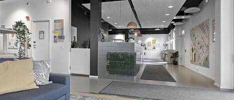 Un interior moderno con una mesa de recepción, un sofá azul y una alfombra estampada.