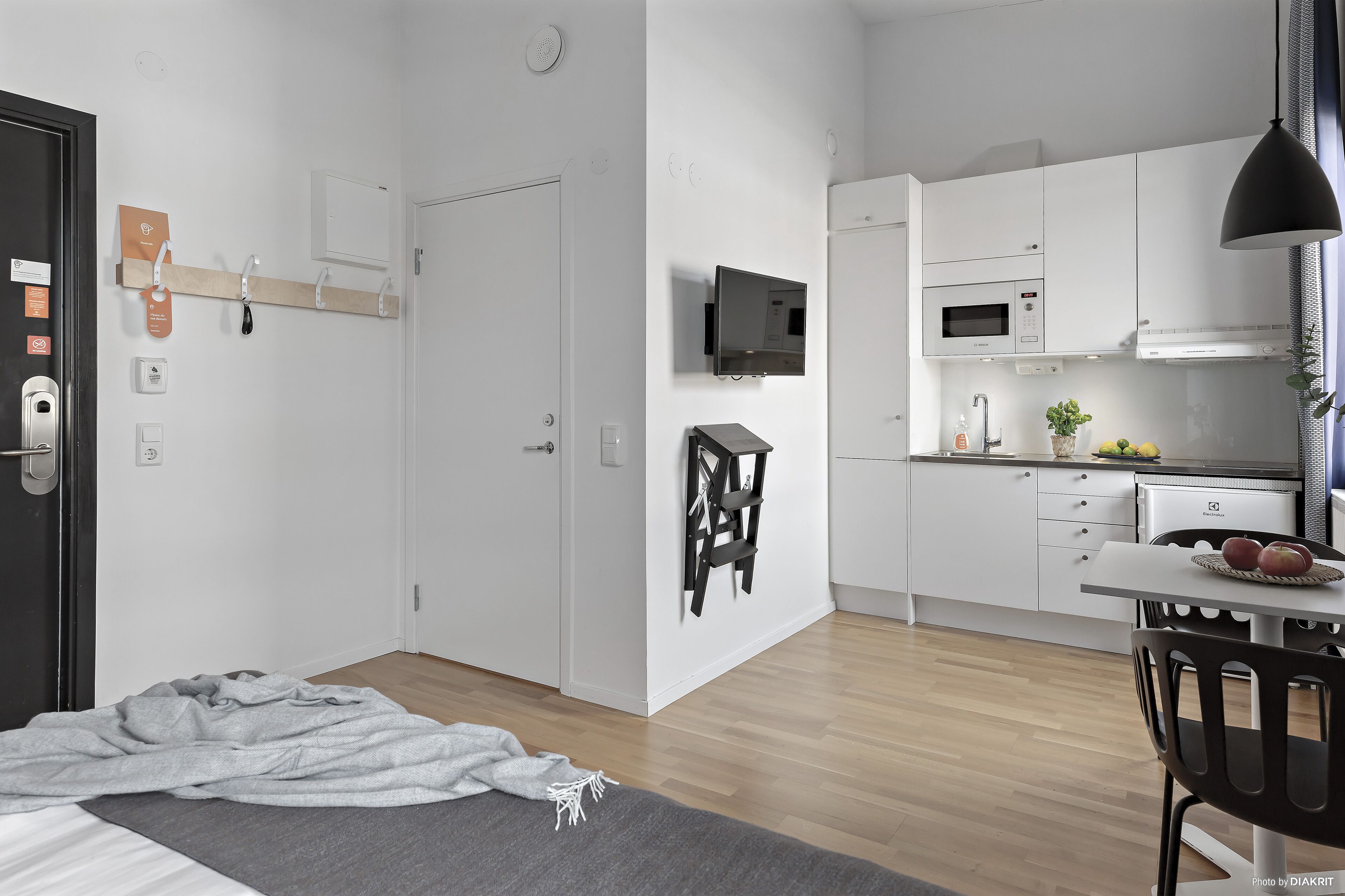 Een modern, minimalistisch appartement met een slaapkamer, kitchenette en een eethoek.