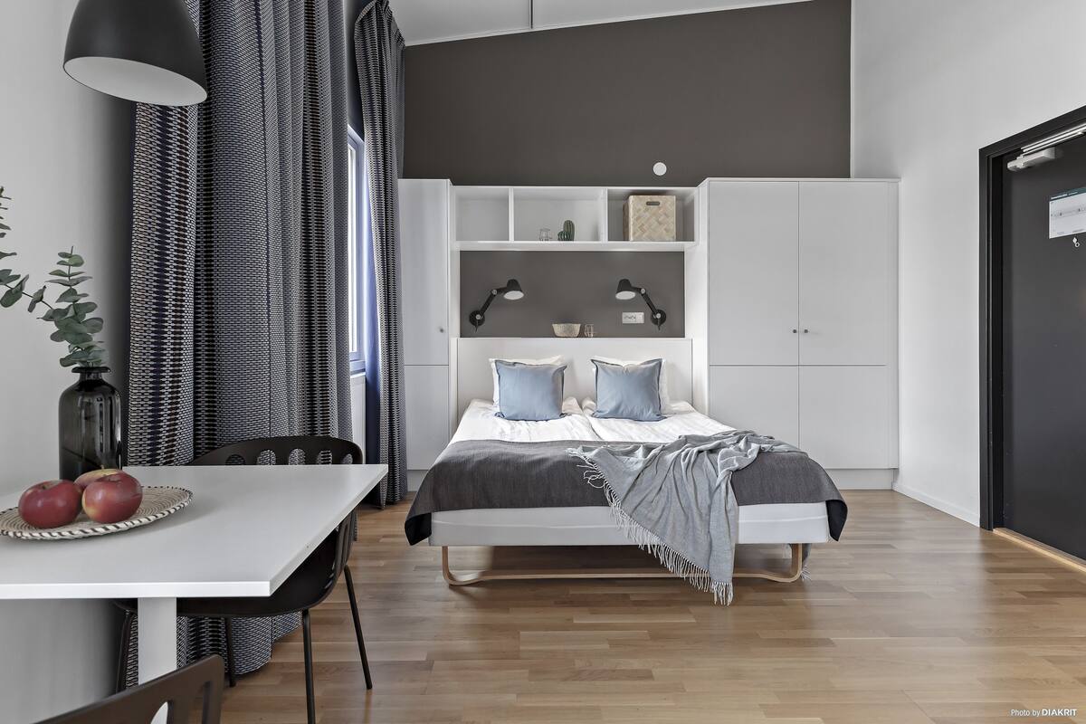 Un dormitorio moderno con cama, mesitas de noche, un escritorio y un armario.