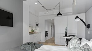 Ein modernes Schlafzimmer mit Bett, Schreibtisch und einer Küchenzeile.
