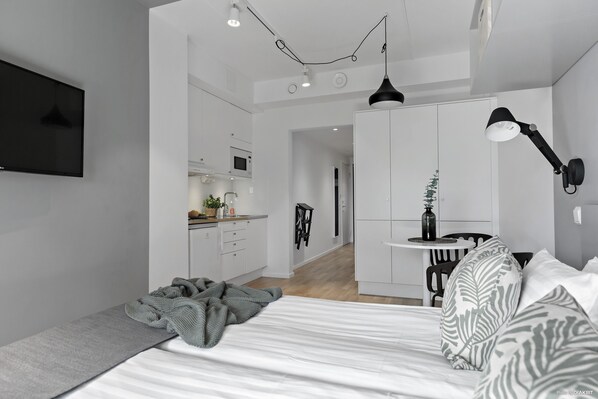 Un dormitorio moderno con una cama, un escritorio y una kitchenette.