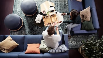 Un salon moderne avec un canapé bleu, une table basse et un jeu de société.