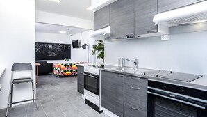 Una cucina moderna con mobili grigi, un lavello in acciaio inossidabile e un piano cottura nero.