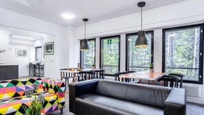 Un interno moderno con un divano in pelle nera, un divano con un motivo geometrico colorato e un'area pranzo illuminata dalla luce naturale proveniente da ampie finestre.