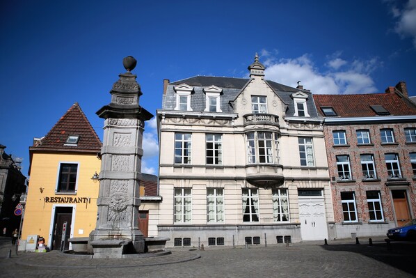 A historic building with a prominent statue in front, a yellow building labeled "RESTAURANT" to the left, and a brick building to the right. - Apart - Hotel Saint Georges (Mons)