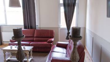 A living room with a red leather sofa, a small table, and two decorative vases.