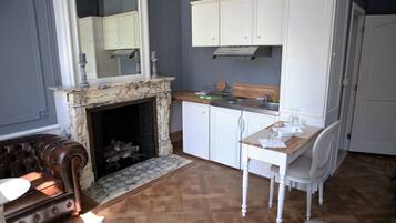 A living room with a fireplace, a dining area with a table and chairs, and a kitchen with white cabinets.