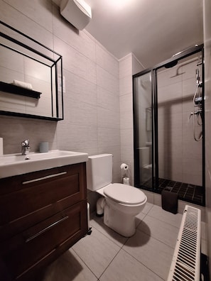 Een moderne badkamer met toilet, wastafel en douche.