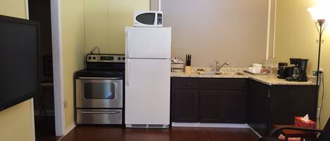 A compact kitchen with a refrigerator, microwave, stove, and sink.