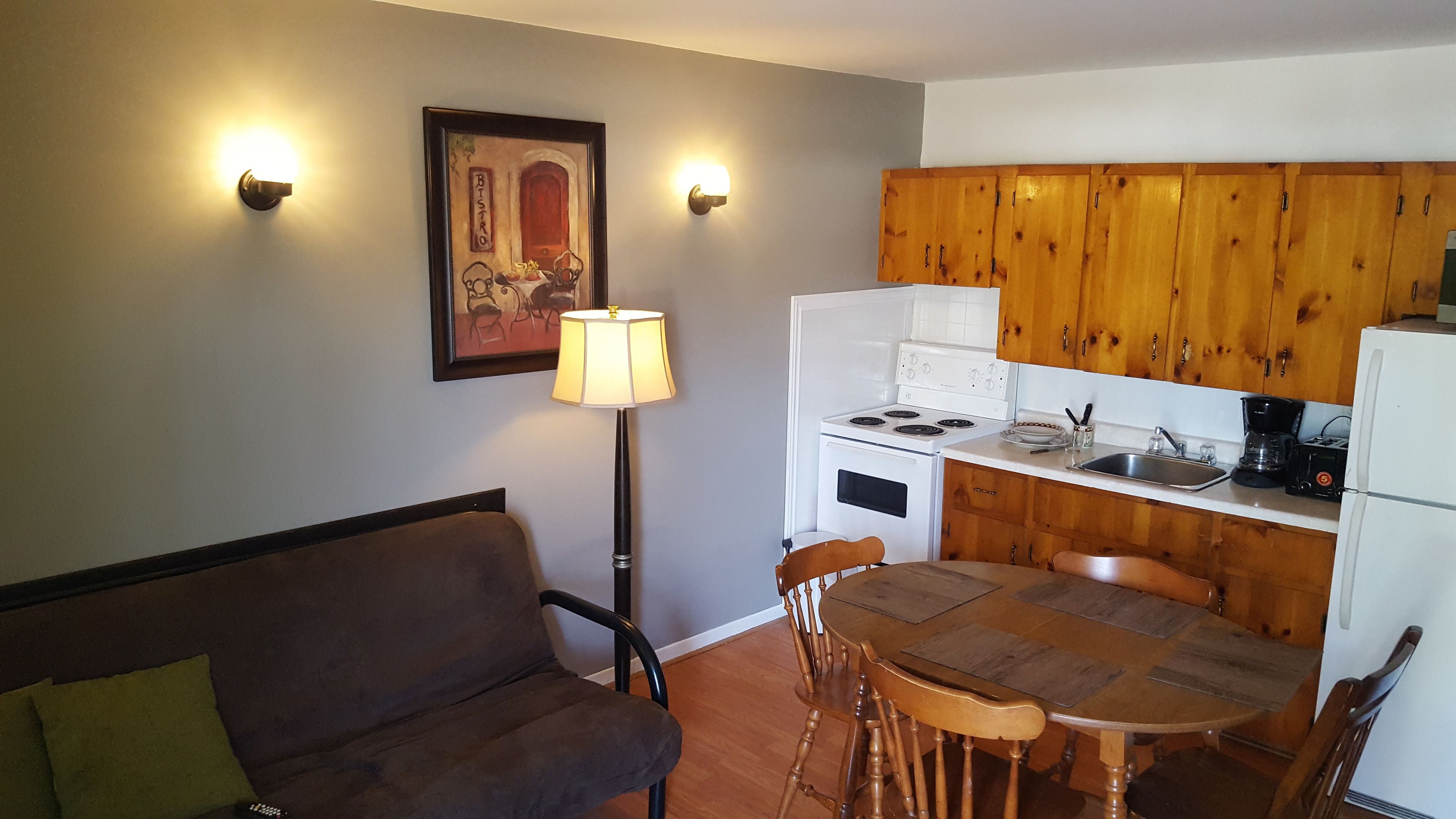 A compact kitchen with wooden cabinets, a white stove, and a dining table with chairs.