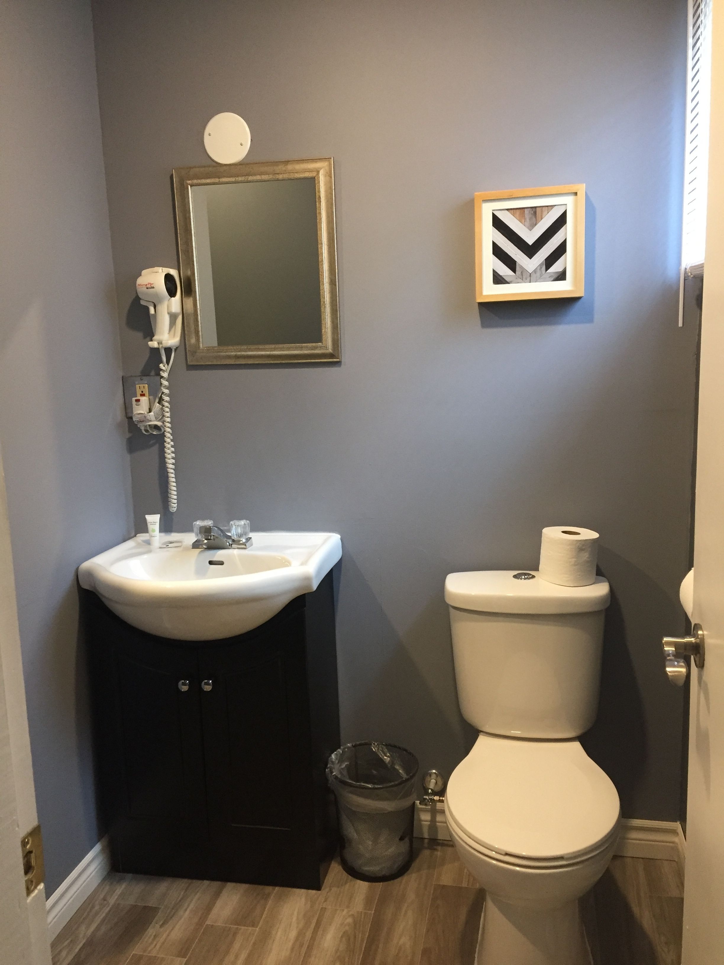 Un baño con lavamanos, espejo, inodoro y cubo de basura.