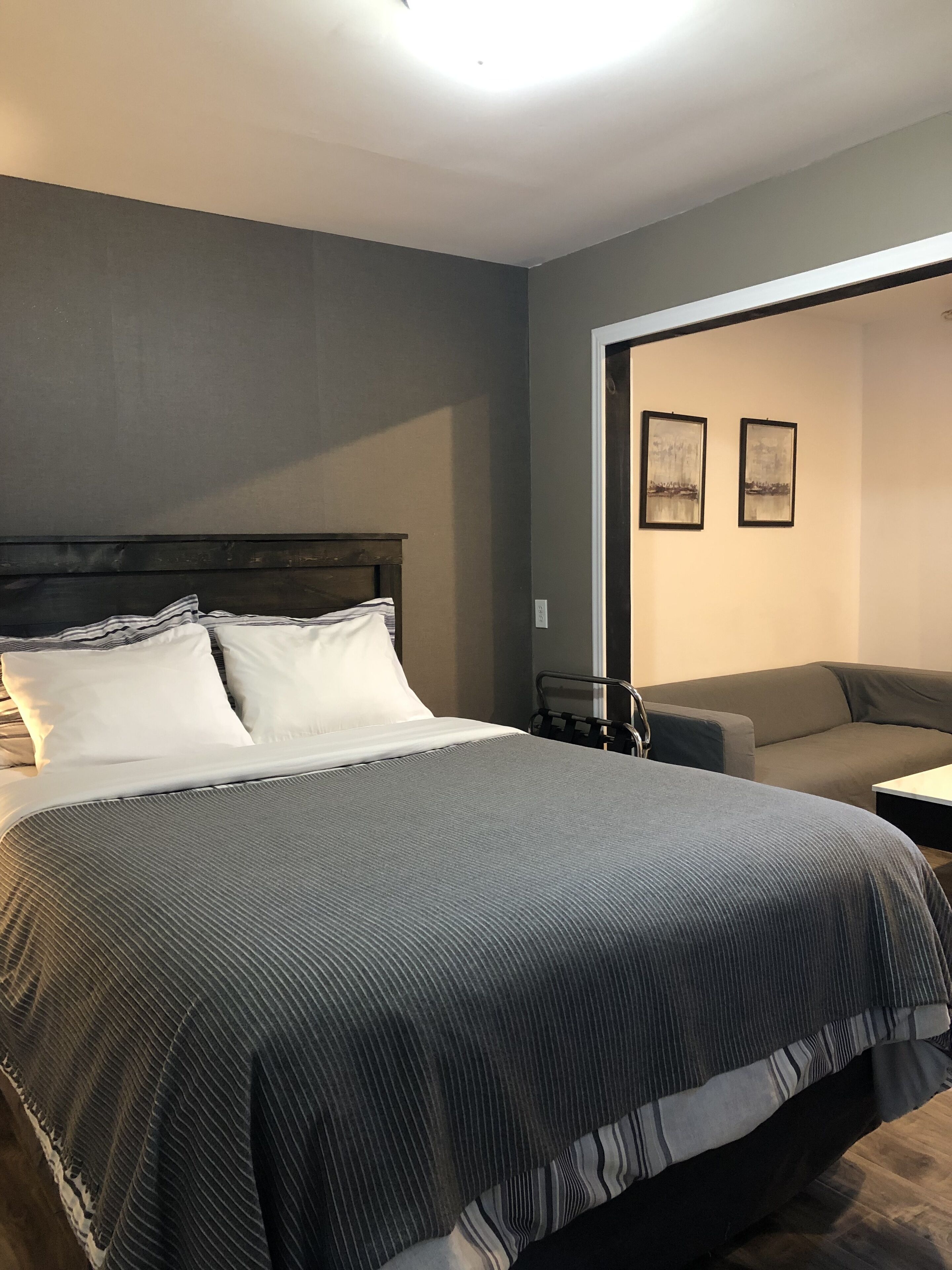 Un dormitorio con una cama grande, un sofá pequeño y dos cuadros en la pared.