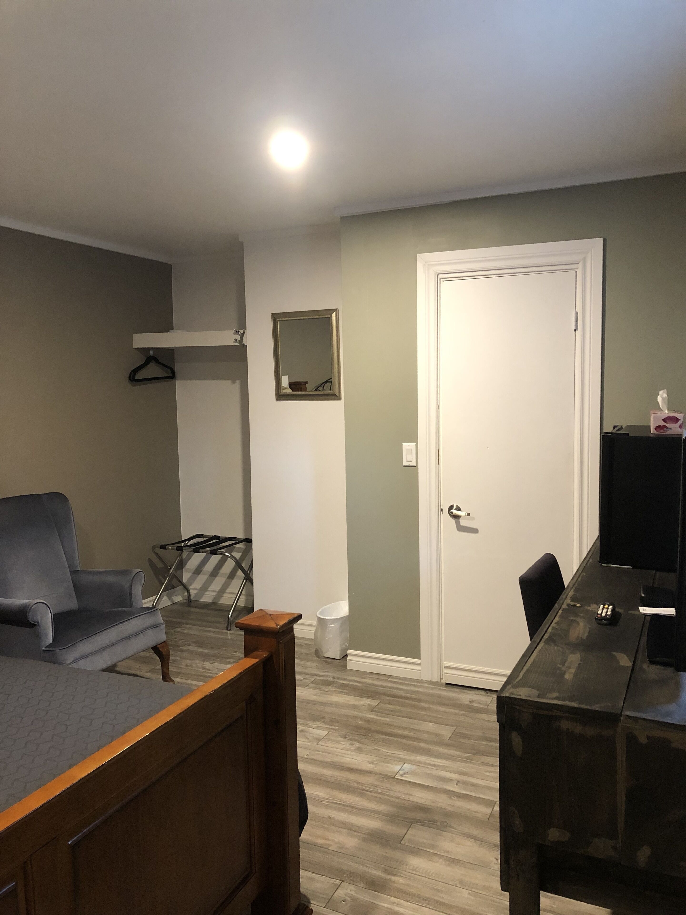 Quarto com cama, escrivaninha, cadeira, cabideiro e porta.