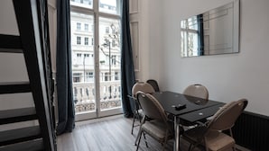 Una habitación con una mesa de comedor, sillas, un ventanal con cortinas y un muro espejado.