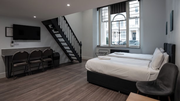 Una habitación moderna con cama, escritorio, sillas y una escalera.