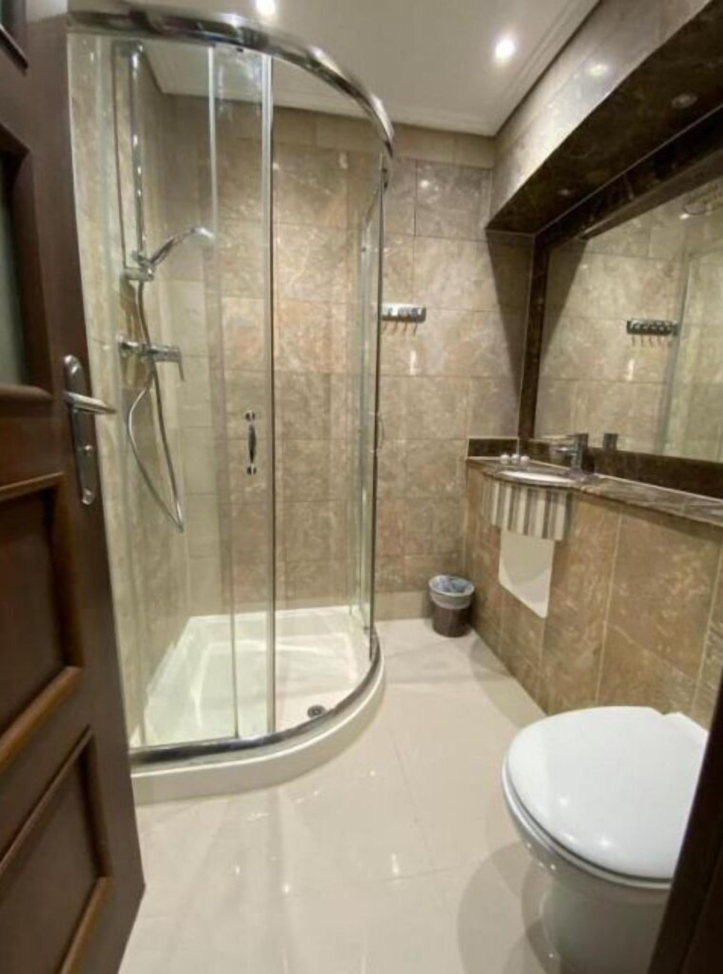 Un baño moderno con ducha de vidrio, inodoro y tocador con espejo.