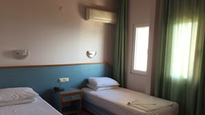 A hotel room with two beds, a nightstand, a wall-mounted air conditioner, and a window with curtains. - Konak Hotel (Alanya)