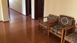 A hallway with a wooden chair and a sofa, a tiled floor, and wooden doors. - Konak Hotel (Alanya)