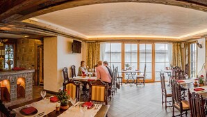 A dining area with a fireplace, large windows, and a mural. - Argo Trakai (Trakai)