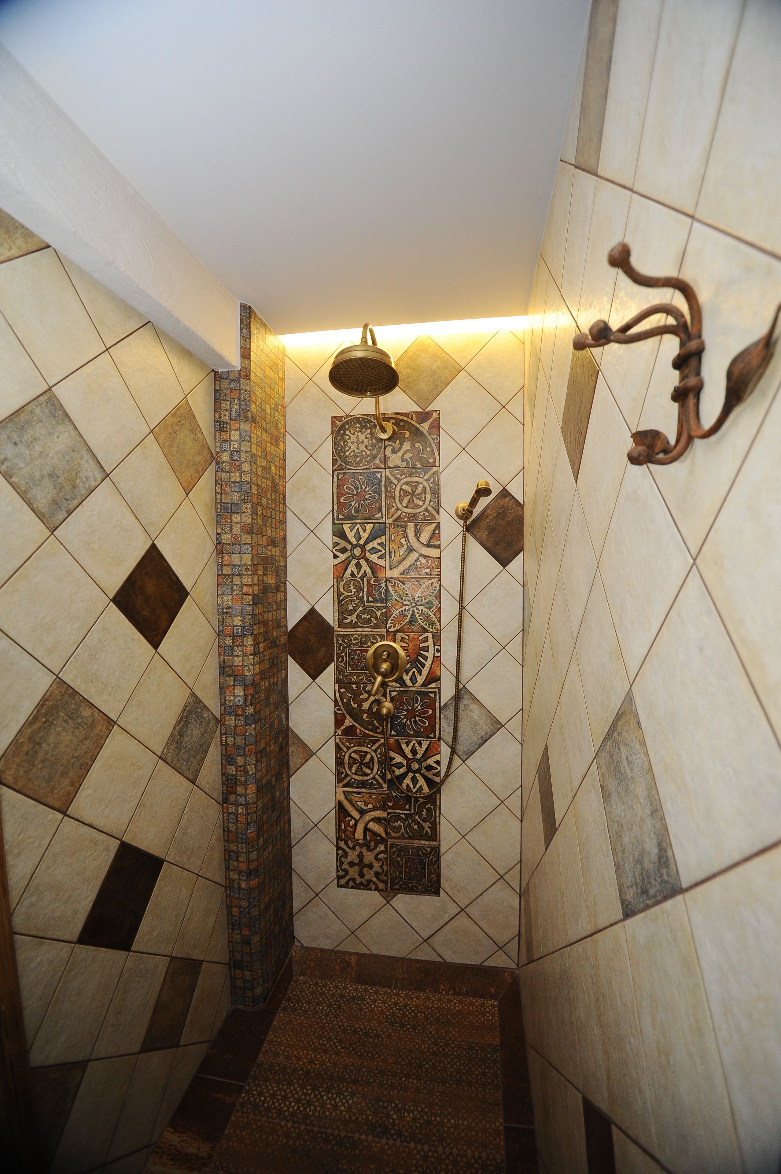 Zona de ducha con azulejos estampados y un cabezal de ducha empotrado.