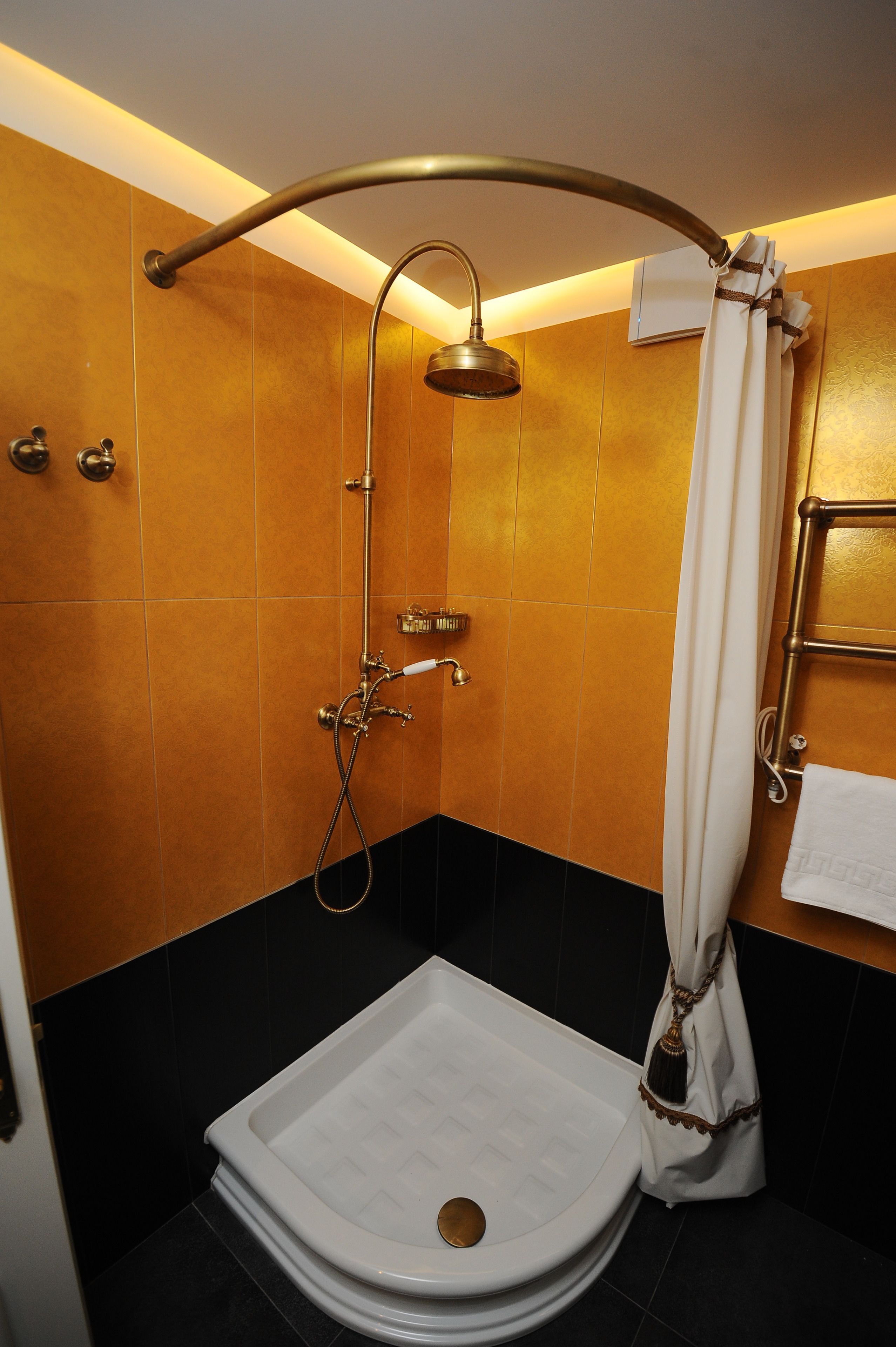 Un baño moderno con ducha de aro, una bañera blanca y un perchero.