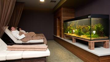 Une salle de spa dotée d’un grand aquarium, d’une table de massage et d’un mur recouvert de panneaux en bois.