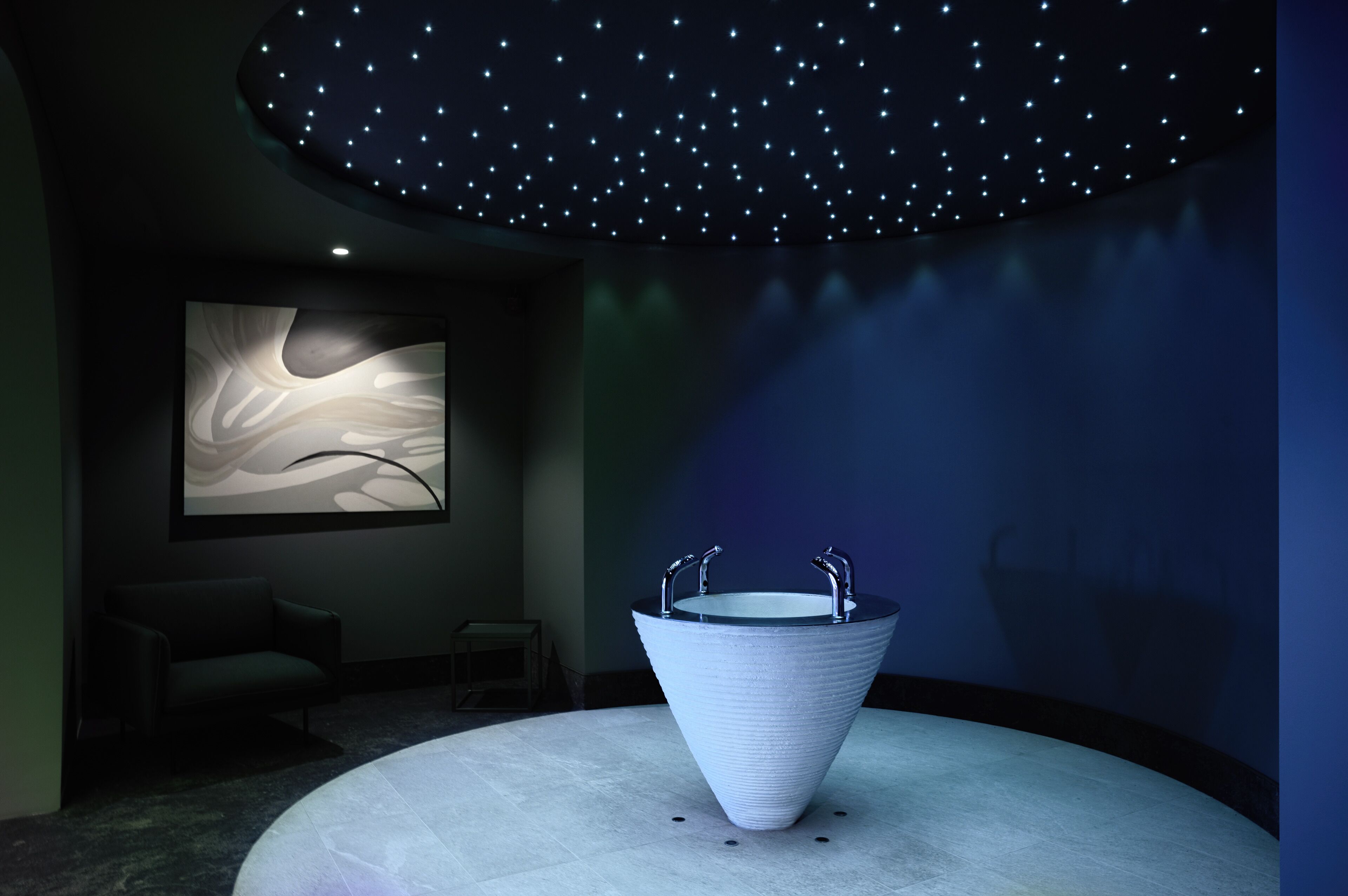 Une salle de bain moderne avec un plafond étoilé, une grande œuvre d’art abstraite et un lavabo au design original.