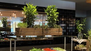 A buffet setup with various dishes, wooden planters with greenery, and a modern kitchen backdrop. - SPA VILNIUS Druskininkai (Druskininkai)