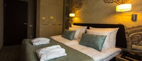 Una habitación de hotel con cama, dos lámparas de noche, una mesita de noche y un armario.