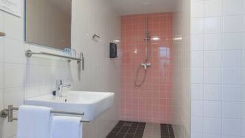 A modern bathroom with a white sink, a mirror, and a shower area.