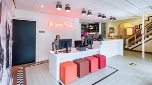 Ett receptionsområde med en vit receptionsdisk, flera datorskärmar och en neonskylt.