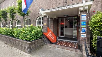The entrance of Kloosterhotel de Soete Moeder with a brick facade, arched windows, and a flag.