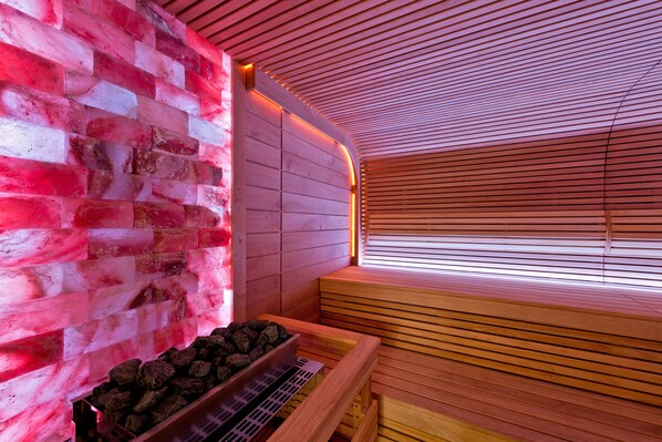Een sauna met een houten bank, een stenen muur en een houten plafond.