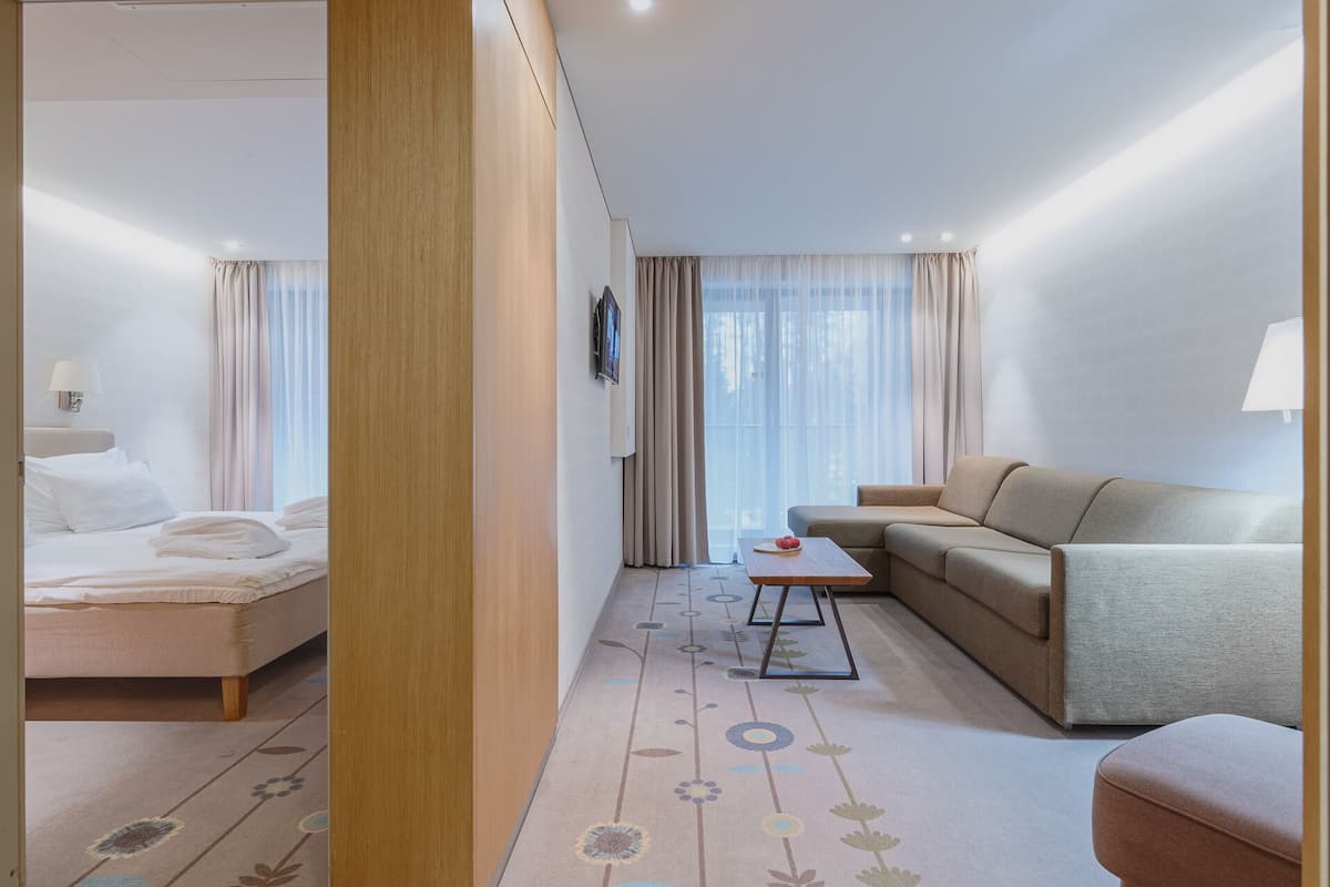 Ein Hotelzimmer mit Bett, einer Sitzecke, einem kleinen Tisch und einem Fenster mit Vorhängen.