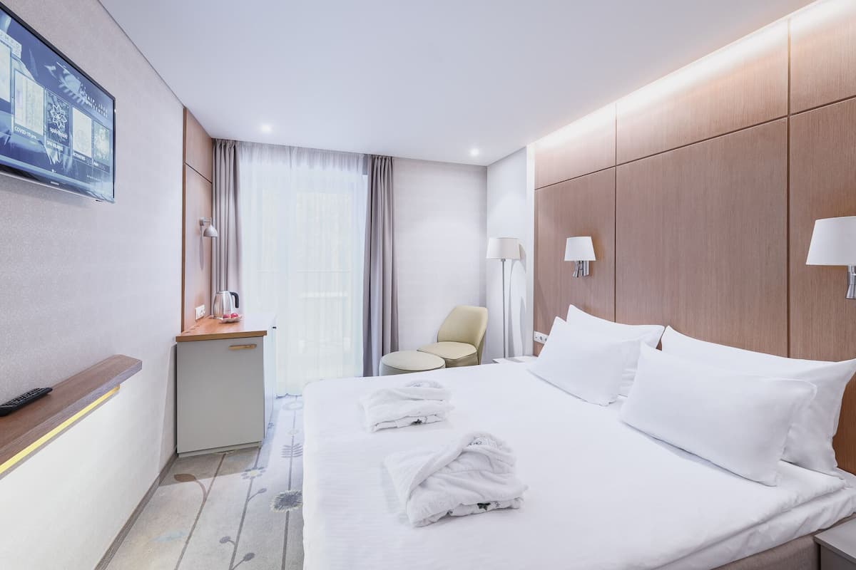 Ein Hotelzimmer mit einem Bett, einem Schreibtisch, einem Stuhl und einem Fernseher an der Wand.