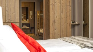 A bedroom with a bed, a red pillow, and a fur throw. There is a wooden wardrobe and a mirror on the wall. - SOWELL Family Valfréjus (Modane)